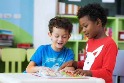 Student in preschool reading a magazine book together in school library